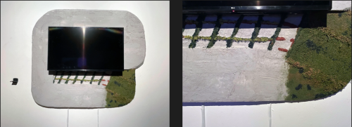 Image of a monitor mounted on a white board with a green substance at the bottom left. Detail of this to the right.