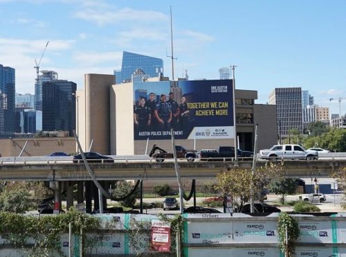 View of APD headquarters and billboard that reads "Together we can achieve more" from across I-35