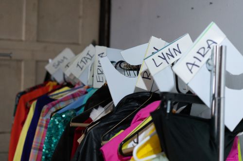 Costume rack backstage labeled by actor first name